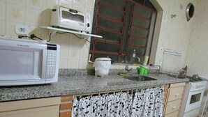 A kitchen with a microwave, sink, and stove. There is a window above the sink and a curtain with a cow pattern hanging over the counter. - ACHIEVING SITE Ground floor, WI FI, Heated pool option, BBQ, Ping Pong (Pinhalzinho)