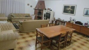 A living room with a fireplace, a dining table, and a sofa. - ACHIEVING SITE Ground floor, WI FI, Heated pool option, BBQ, Ping Pong (Pinhalzinho)