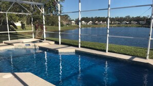 A swimming pool with a clear view of a lake and houses in the background. - Renovated Waterfront 4Bd/2Bth Home w/Pool&Spa 20Min to Disney/Shops/Universal (Kissimmee)