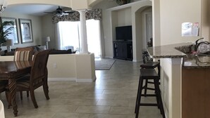 A spacious living area with a dining table, chairs, and a kitchen area with a countertop and sink. - Renovated Waterfront 4Bd/2Bth Home w/Pool&Spa 20Min to Disney/Shops/Universal (Kissimmee)