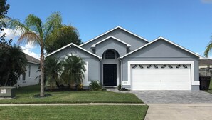 A modern two-story house with a garage, a well-maintained lawn, and palm trees. - Renovated Waterfront 4Bd/2Bth Home w/Pool&Spa 20Min to Disney/Shops/Universal (Kissimmee)