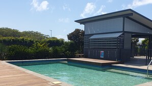 Uma piscina com deck de madeira e área coberta.