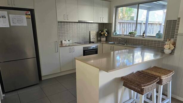 Cozinha moderna com uma ilha grande, eletrodomésticos de aço inoxidável e vista para o exterior.