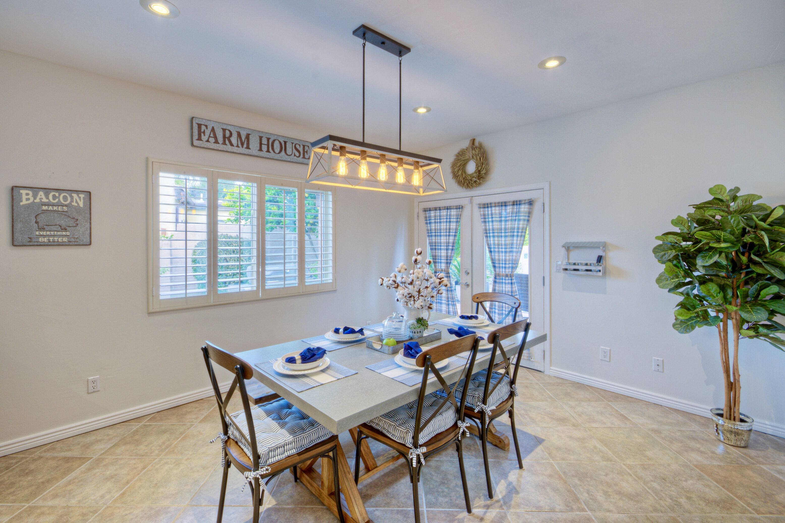 A dining area with a farmhouse sign, a chandelier, and a potted plant.
