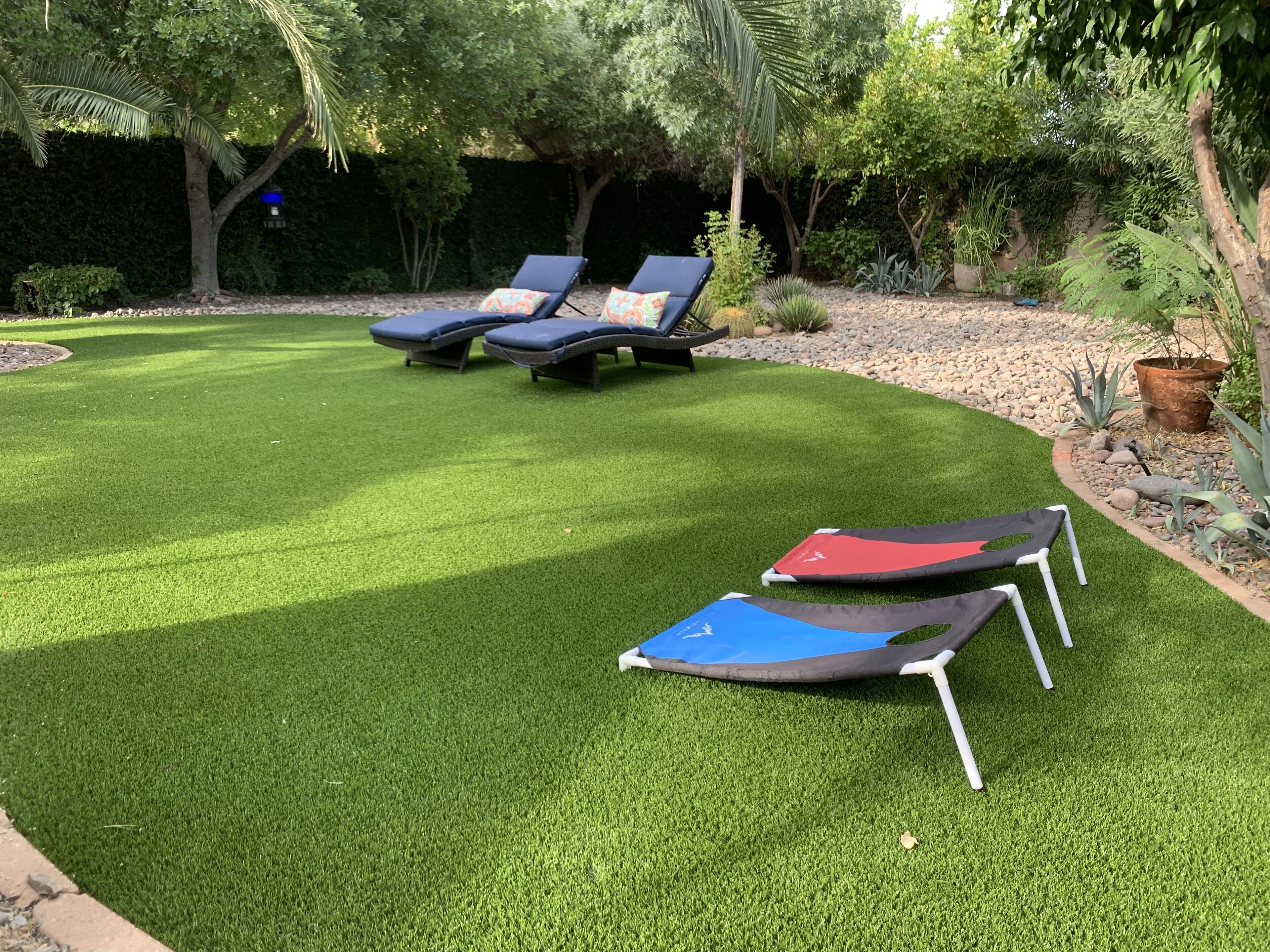A well-maintained lawn with two lounge chairs and a small trampoline.