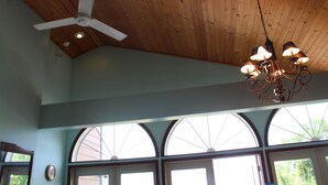 A room with a wooden ceiling, a ceiling fan, and a chandelier. There are large arched windows allowing natural light. - BEACHFRONT /HOTTUB/STEAM ROOM/GAME ROOM/JACUZZI/PETS/MASSAGE CHAIR/KAYAKS/BIKES (Michigan City)