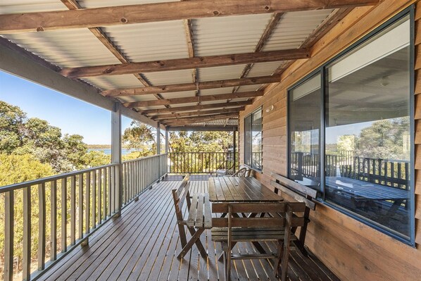 A wooden deck with a metal roof, a table, and benches.