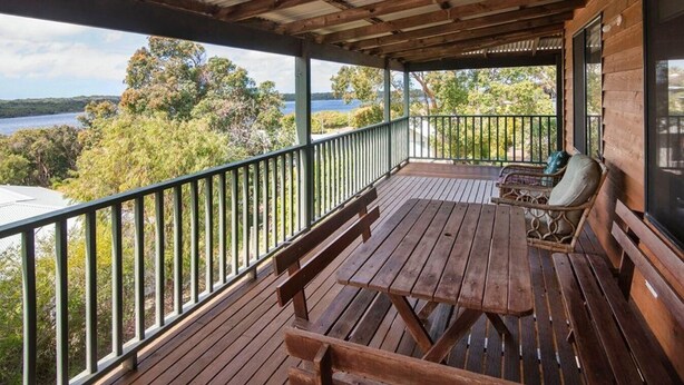 A wooden deck with a railing, a table, and two chairs. - Waterside View - A family-friendly retreat - Waterside View - family-friendly retreat with stunning Blackwood River views (Augusta)