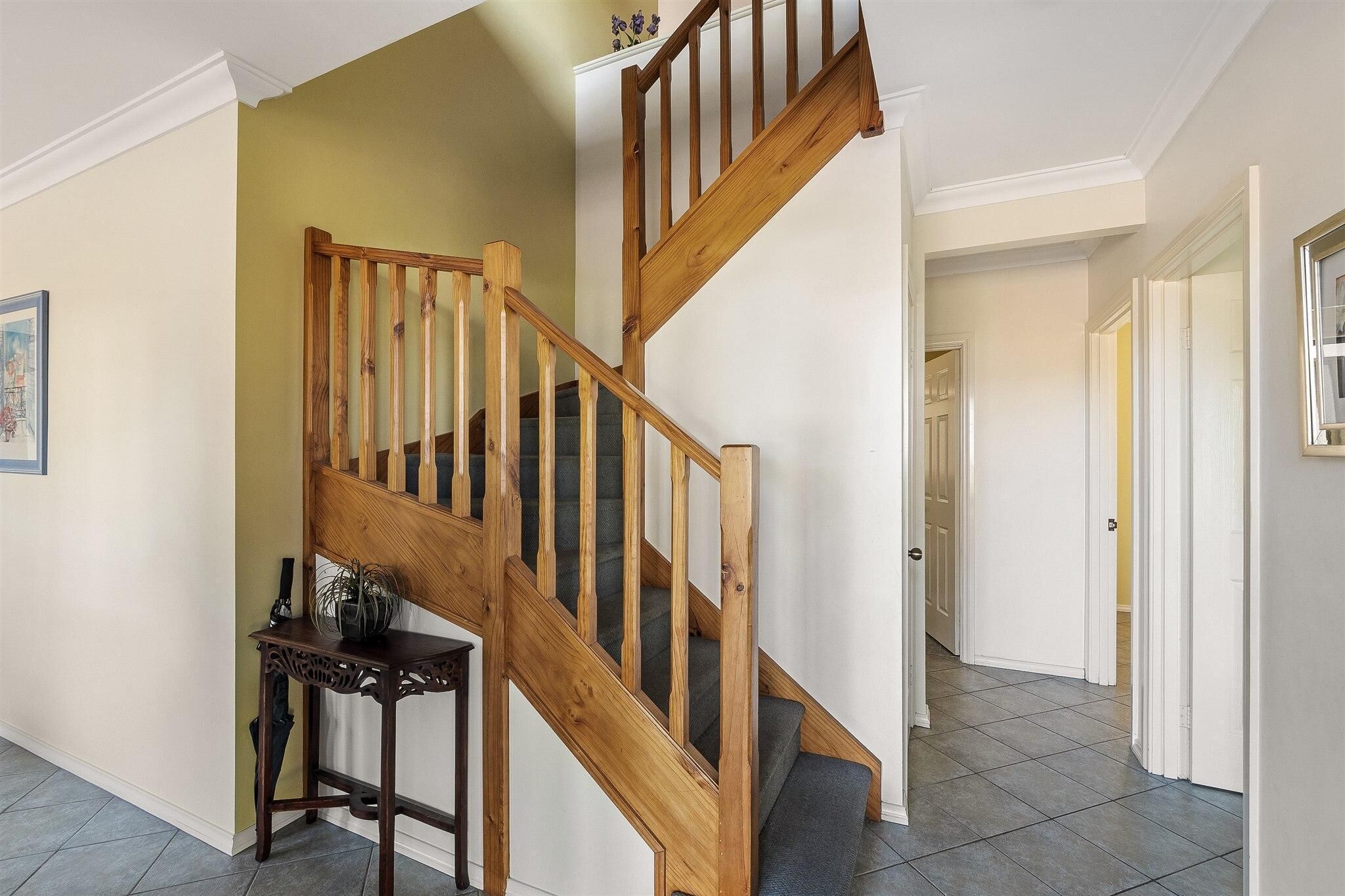 Una escalera de madera con una mesa de madera oscura a su lado.