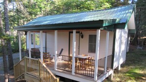 A cabin with a porch, wooden deck, and outdoor seating area.