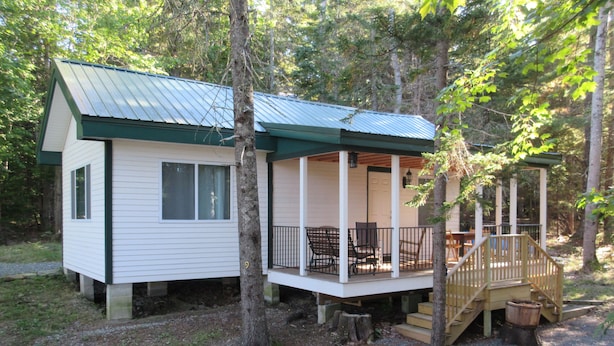 A cabin with a porch, a staircase, and a deck.