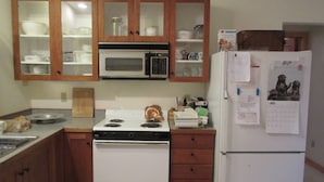 A kitchen with wooden cabinets, a microwave, a stove, and a refrigerator.