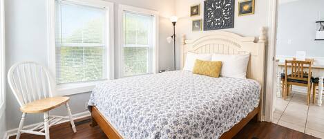 Un dormitorio con cama, una silla, un escritorio y una ventana con persianas.