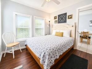 Een slaapkamer met een bed, een stoel, een bureau en een raam met jaloezieën.