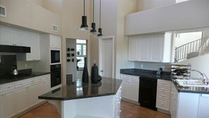 A modern kitchen with white cabinetry, a black countertop, and a built-in dishwasher.