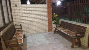 Un patio al aire libre con pared de ladrillo, banco de madera, una mesa pequeña y planta en maceta.