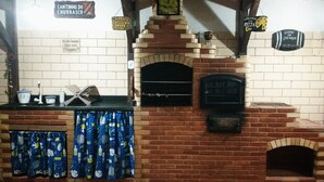Horno de ladrillo para pizzas con un reloj encima, un letrero que dice 'Cantinho da Pizzas' y un letrero que dice 'Clube da Cachaca'.
