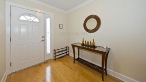 A hallway with a white door, a small table with bottles, and a decorative mirror on the wall.