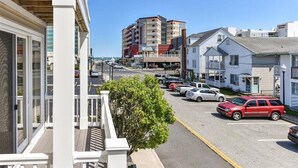 A street view with a row of parked cars, a building with a sign, and a clear blue sky.