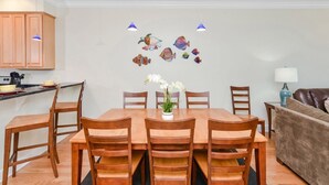 A dining area with a wooden table and chairs, a vase with flowers, and wall art of fish.