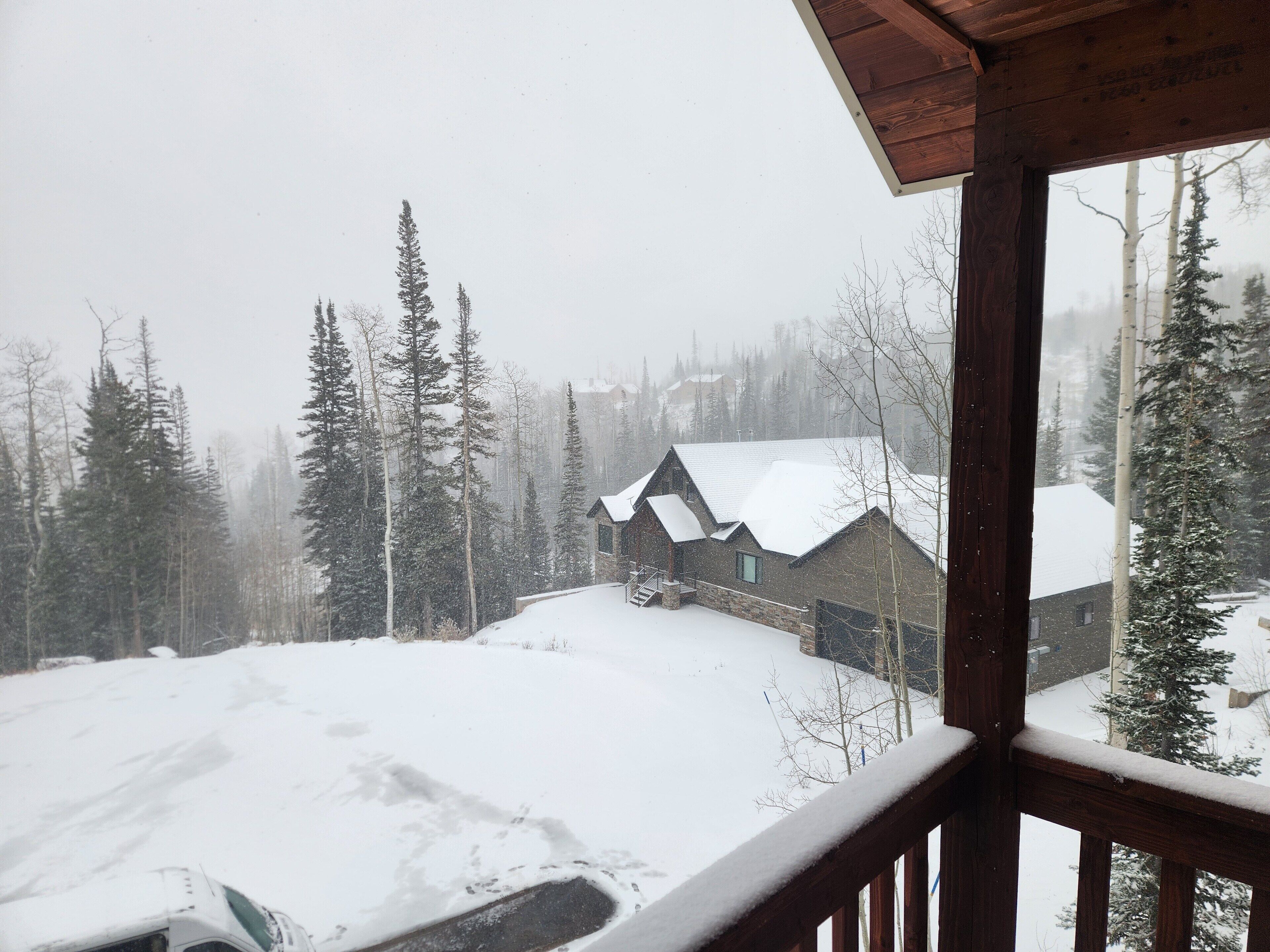 Une cabane dont le toit est recouvert de neige et qui possède une terrasse en bois.