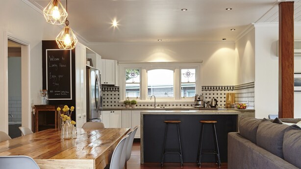 A modern kitchen with a wooden dining table, bar stools, and a built-in island. - Lumley House Bright c1898 (Bright)