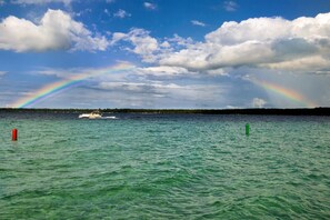 Un bateau sur une étendue d’eau, avec un arc-en-ciel en arrière-plan.