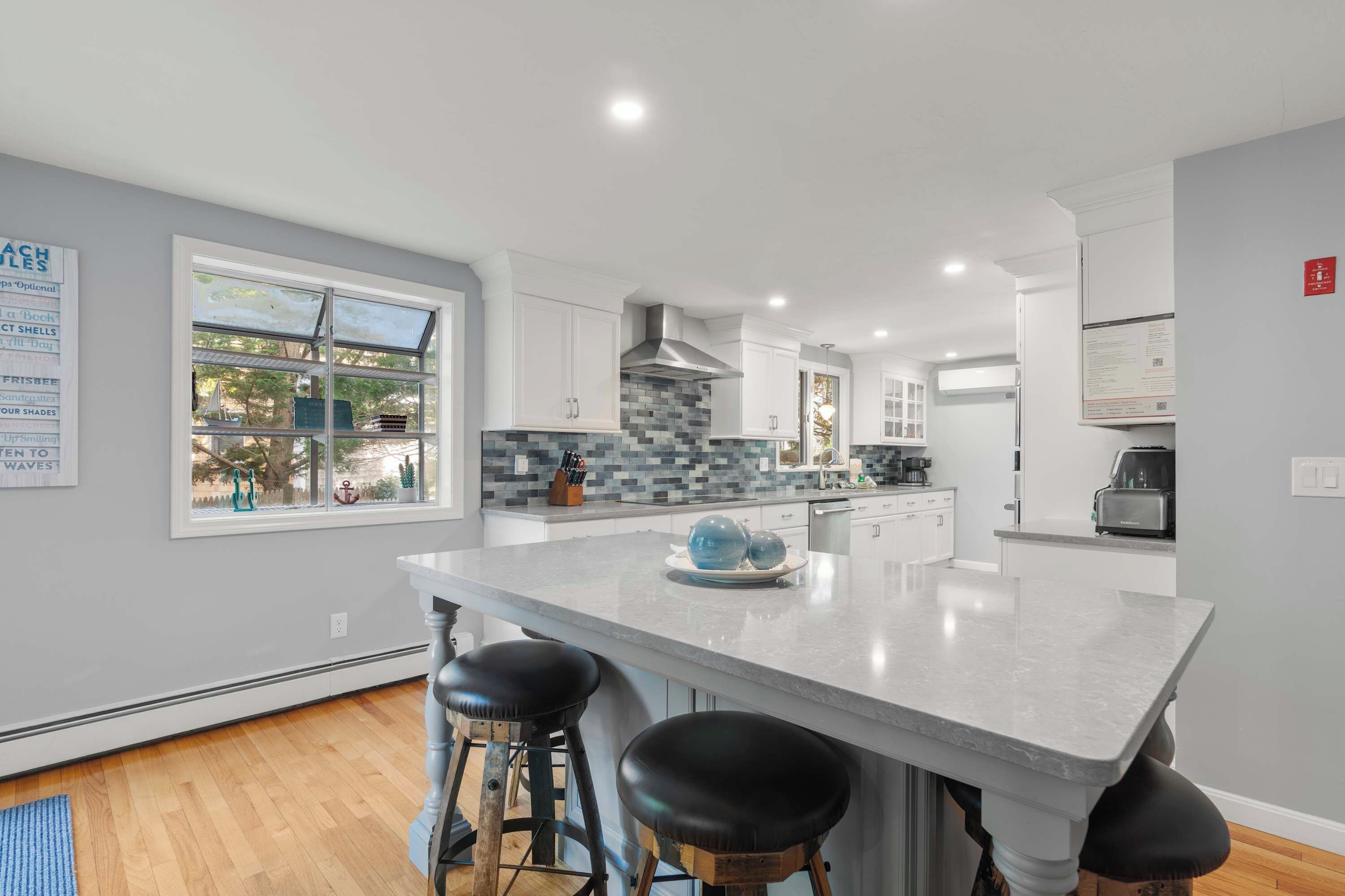 A modern kitchen with a large island, bar stools, and a view of the outdoors.