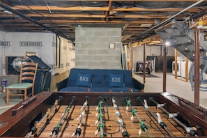 Una habitación con mesa de fútbol de mesa, un sofá azul y una silla.