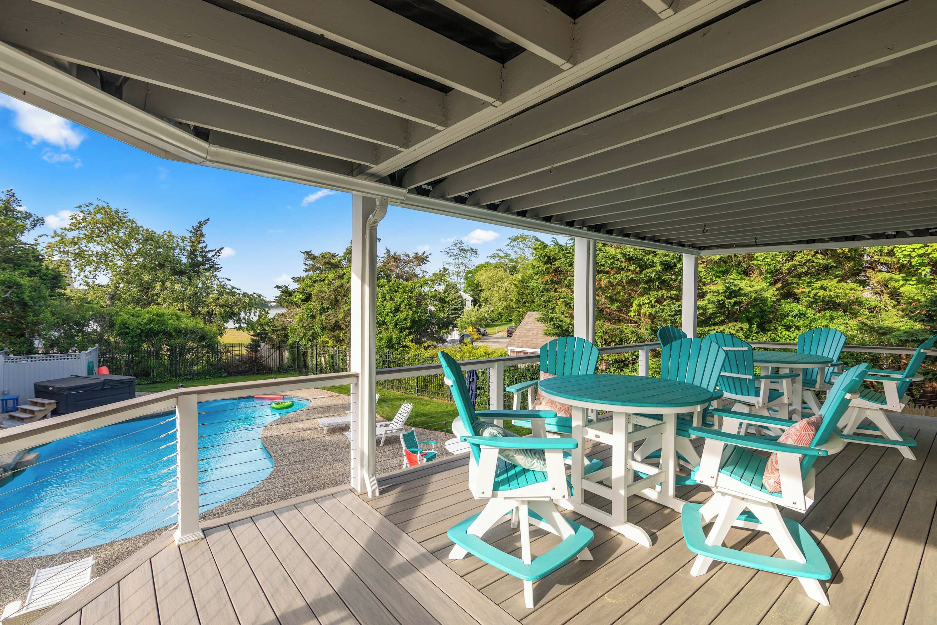 Um deck coberto com piscina, móveis de exterior e vista para o verde ao redor.