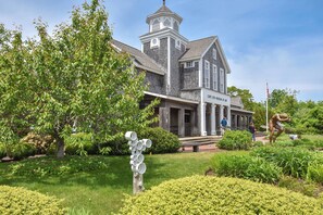 Ein historisches Gebäude mit einem Turm, einem Schild mit der Aufschrift „Cape Cod Museum of Art“ und einer Skulptur eines Mannes in dynamischer Pose.