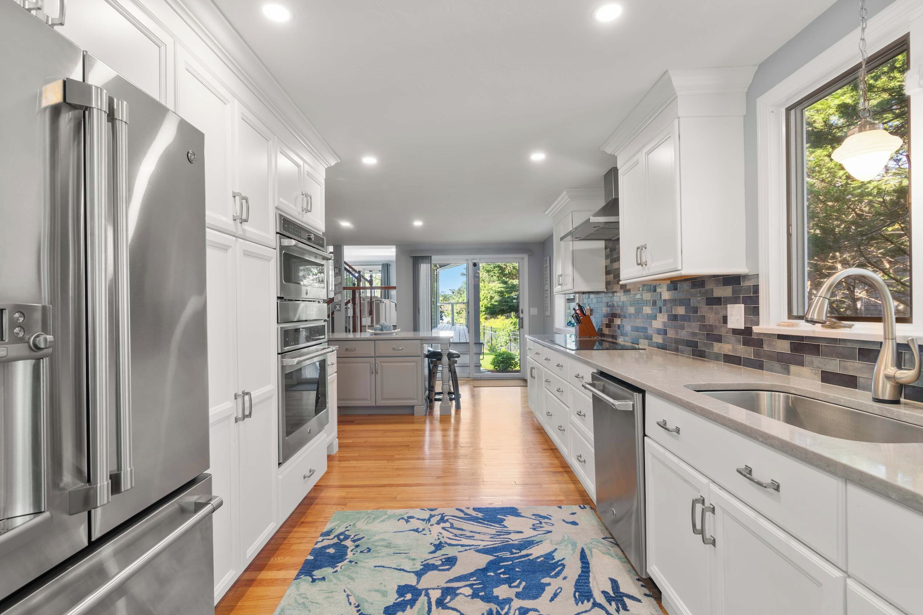 A modern kitchen with stainless steel appliances, white cabinetry, and a view to the outdoors.