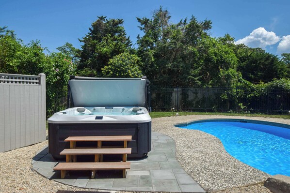 Ein Whirlpool mit Treppen, ein Schwimmbecken und ein Holzzaun.