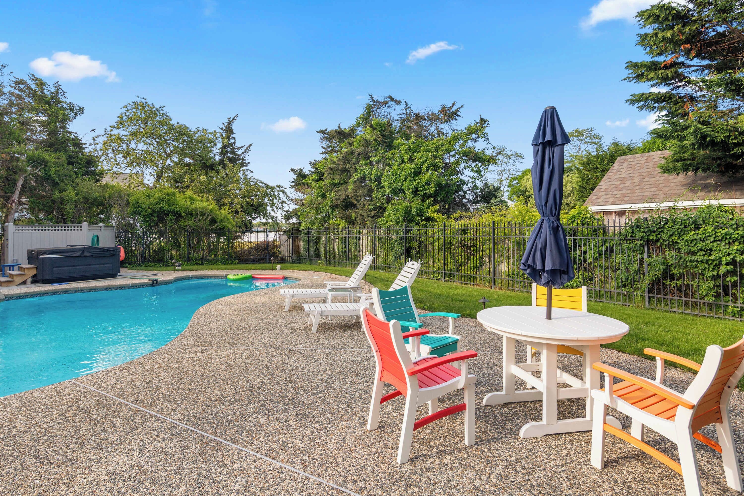 Una piscina con sillones de descanso y una mesa.