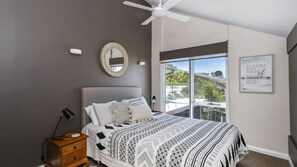 A bedroom with a large bed, a ceiling fan, a view of the outdoors, a mirror, and a motivational quote on the wall. - Surfers Reef Escape in Mollymook (Mollymook Beach)