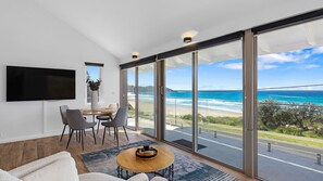 Un salon moderne doté d’une grande porte-fenêtre coulissante donnant sur un balcon avec vue sur l’océan.