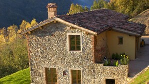 A stone house with a tiled roof, two windows, and a small porch area. - Tuscan Farmhouse in Hills w/Stunning Views - Private Pool, near Barga (Treppignana)