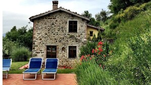 A stone house with a pool and blue lounge chairs. - Tuscan Farmhouse in Hills w/Stunning Views - Private Pool, near Barga (Treppignana)
