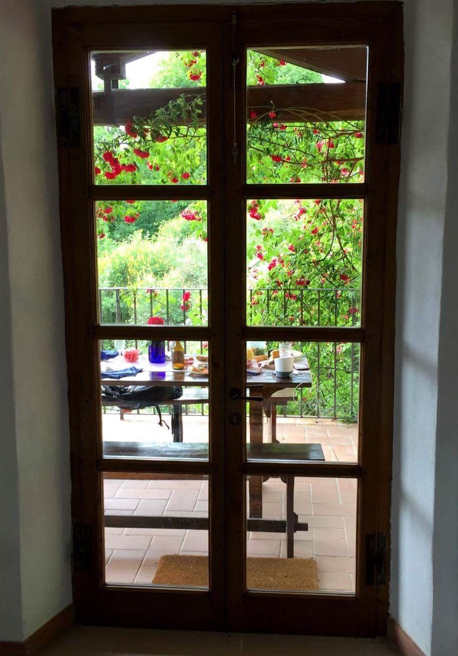 Eine Holztür mit Glaseinsätzen, die zu einer Außenpatio mit Tisch und Stühlen führt.