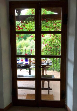 A wooden door with glass panels, leading to an outdoor patio with a table and chairs.