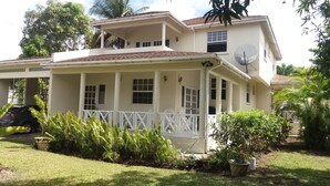 A two-story house with a covered porch, satellite dish, and potted plants.