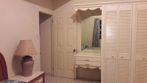 A bedroom with a bed, a bedside table with a lamp, a wardrobe, and a mirror.