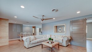 Un salon moderne avec un canapé d’angle, une table basse et un ventilateur de plafond.