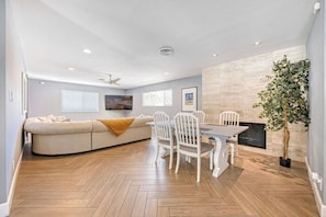 A modern living room with a sofa, dining table, chairs, and a fireplace. - Your Oasis Near the Las Vegas Strip: Vacation Rental Sleeps 8 w Pool & Game Room (Las Vegas)