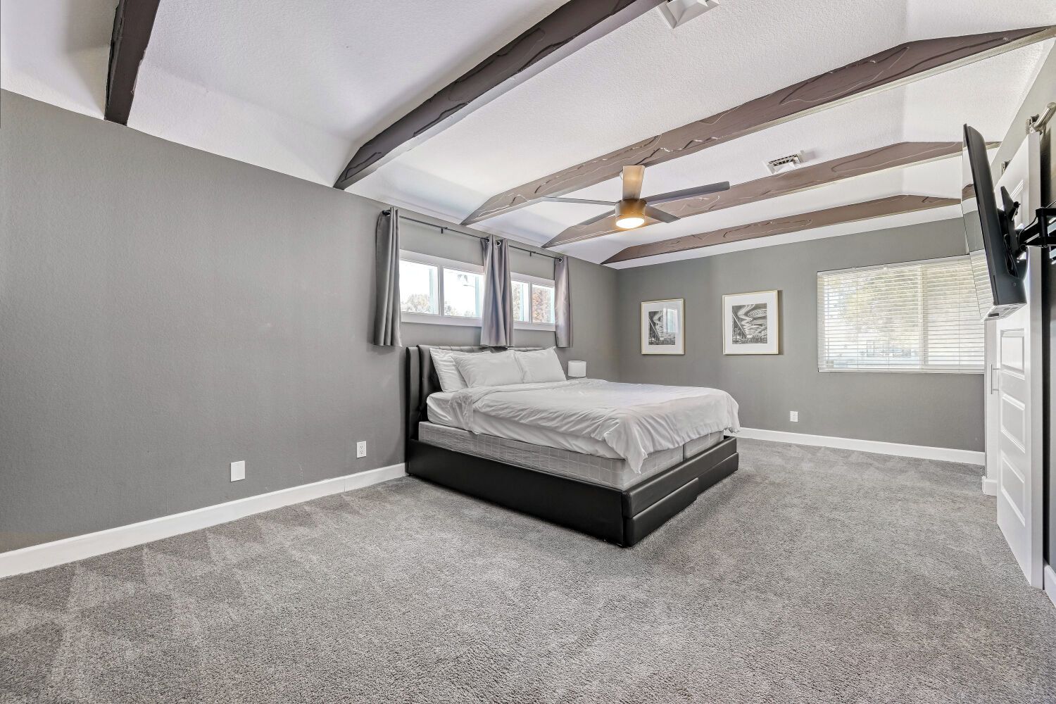 A bedroom with a bed, a ceiling fan, and a window with blinds.