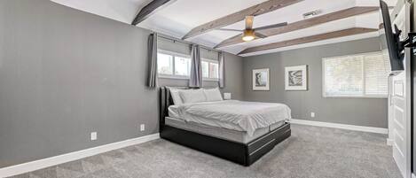 A bedroom with a bed, a ceiling fan, and a window with blinds.