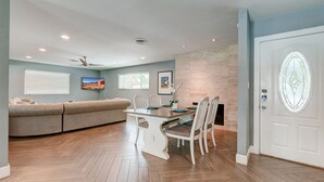 Un coin repas avec une table et des chaises en bois, un canapé et un ventilateur de plafond.