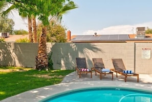 A swimming pool with lounge chairs and a solar panel on the roof.