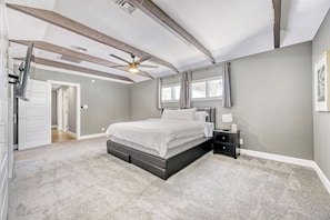 Ein Schlafzimmer mit einem Bett, einem Nachttisch, einem Deckenventilator und einem Fenster.