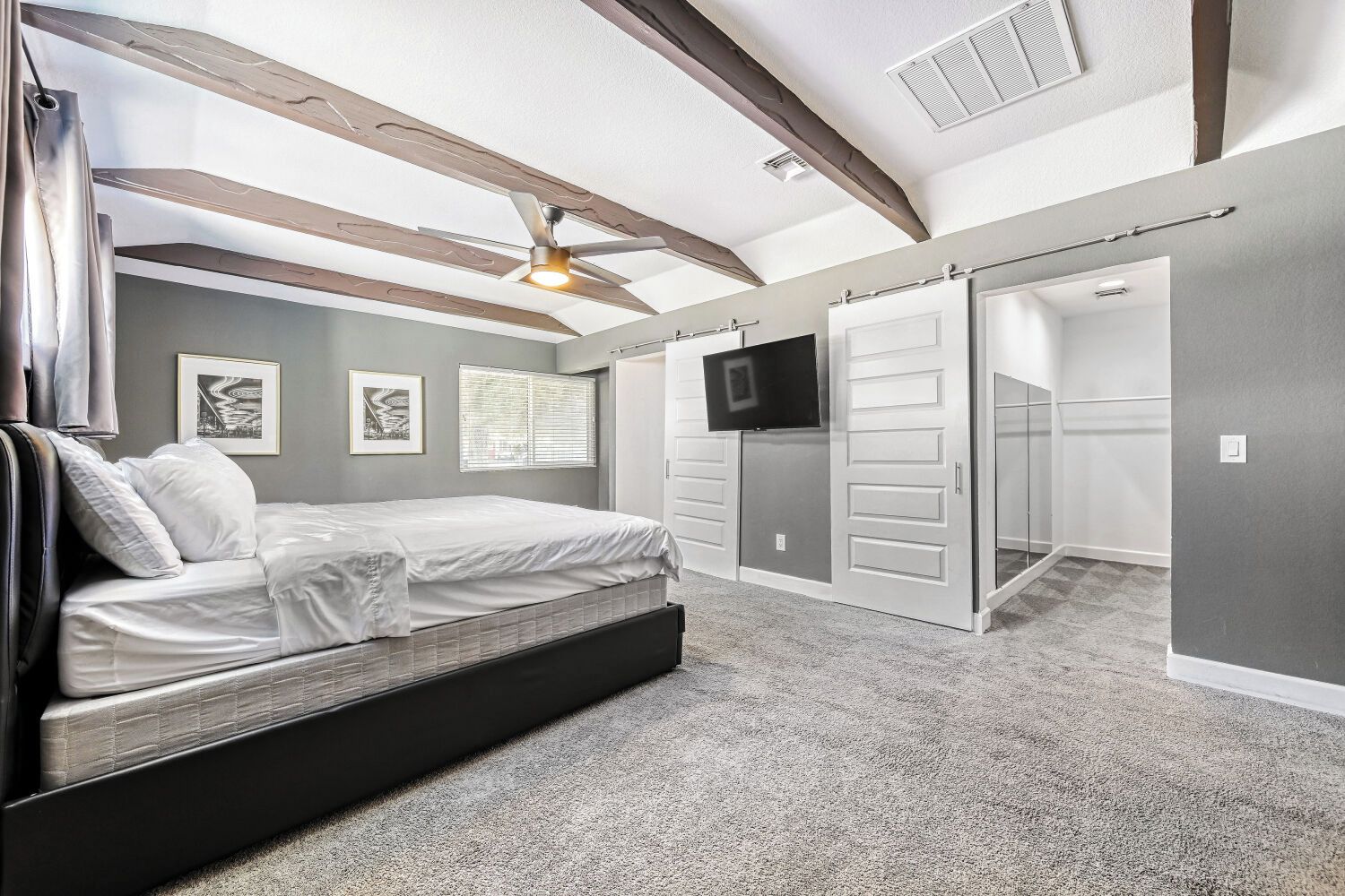Une chambre à coucher avec un lit, une télévision, une armoire et un ventilateur de plafond.